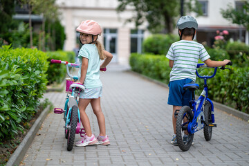 Two confident youngsters enjoy a bike ride in the city, showcasing their friendship and joy. The image highlights health and the importance of safety measures like wearing helmets. 