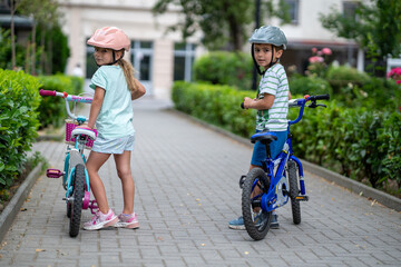 Two confident youngsters enjoy a bike ride in the city, showcasing their friendship and joy. The image highlights health and the importance of safety measures like wearing helmets. 