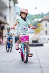 Cute girl wearing cycling helmet and riding bike at park. Portrait of a playful funny girl in a pink safety helmet on her bike