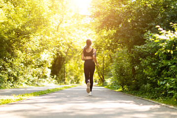 Rear view of African American woman jogging in park on sunny day. Fitness lifestyle, outdoor...