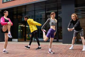 Dynamic group engages in warm up exercises in urban fitness space during the afternoon