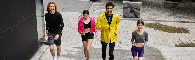 Obraz premium Energetic group of young athletes jogging together on a sunny outdoor pathway