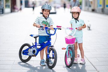 Two confident youngsters enjoy a bike ride in the city, showcasing their friendship and joy. The image highlights health and the importance of safety measures like wearing helmets. 