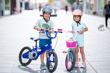 Two confident youngsters enjoy a bike ride in the city, showcasing their friendship and joy. The image highlights health and the importance of safety measures like wearing helmets. 
