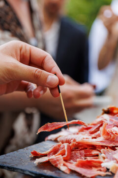 A guest is serving himself a slice of Iberian ham during an afterwork party