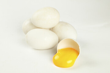 Fresh Free-Range Goose Eggs with Cracked Shell Showing Orange Yolk on White Background