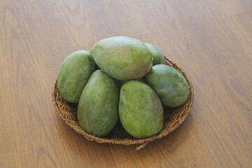 Fresh Green Mangoes in Wicker Basket on Wooden Table - Tropical Fruit Display