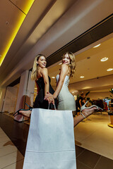 Two girls stand with shopping bags near the entrance to a clothing boutique