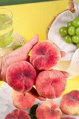 Fresh Red Hairy Flat Peaches from Shaanxi China Held in Hands on Yellow Background