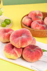 Fresh Flat Peaches from Shaanxi Province China - Ripe Red Fruit on White Board with Wicker Basket