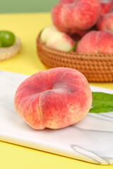 Fresh Shaanxi Flat Bottom Peaches on Cutting Board with Red Peaches in Wicker Basket