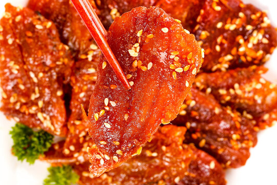 Dried Fish Jerky with Honey Glaze and Sesame Seeds - Traditional Asian Seafood Snack on White Plate