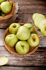 Fresh Green Shandong Apples in Wicker Baskets on Rustic Wood Background