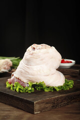 Fresh Whole Pig Elbow Joint Raw Pork Display on Wooden Board with Lettuce Garnish