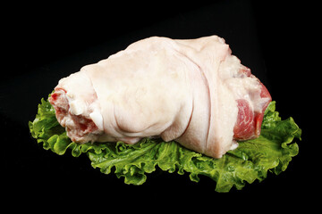 Fresh Raw Whole Pork Leg with Elbows on Lettuce Leaves Black Background
