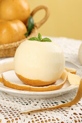 Fresh Golden Pear Fruit Peeled and Sliced with Mint Garnish on White Plate