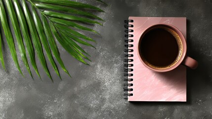In the foreground of a scene with a plant, a table supports a cup of coffee, a notebook, and a pen