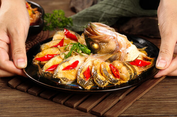 Steamed whole fish with chilies on wooden board - traditional Asian seafood dish presentation