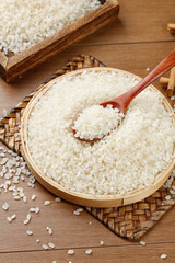 Fresh White Rice Grains in Bamboo Bowl with Wooden Spoon on Rustic Wood Table for Healthy Cooking