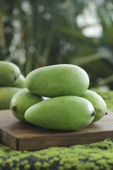 Fresh Green Mangoes on Wooden Board in Tropical Garden Setting