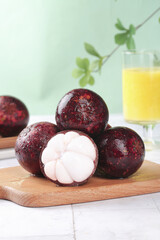 Fresh Thai Mangosteen Tropical Fruit on Bamboo Board with Juice Glass