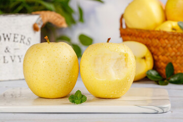 Fresh Yellow Marshal Apples from Xinjiang China on Rustic White Wooden Board with Wicker Basket