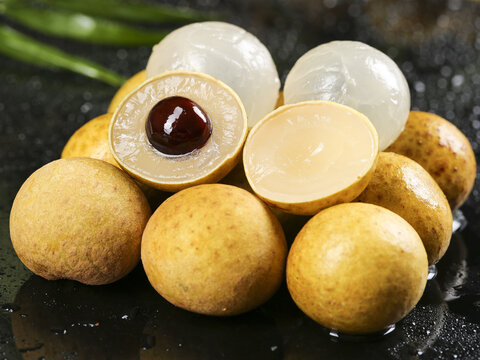 Fresh Longan Tropical Fruits with Translucent Flesh and Seeds on Dark Wet Surface