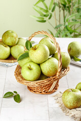 Fresh Green Shandong Apples in Wicker Basket on Rustic Table with Tropical Plants Background