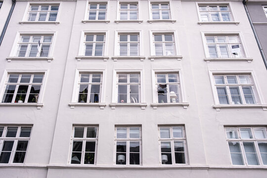 White residential facade with repetitive windows in central Copenhagen, minimal geometry and light atmosphere illustrating urban restoration and European housing continuity