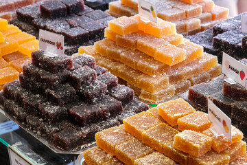 Colorful stacked fruit jellies coated with sugar, displayed in a market with flavors like...