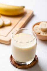 Banana milk in glass with sliced banana and fruit on white background