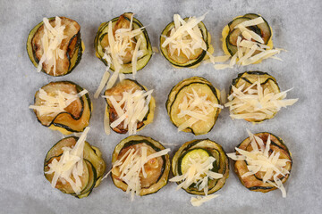 Baked savory polenta bites with fried zucchini, topped with grated parmesan cheese