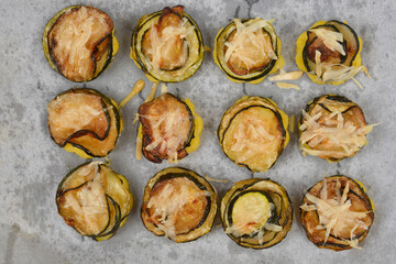 Baked savory polenta bites with fried zucchini, topped with grated parmesan cheese