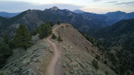 Scenic mountain trail winding through rugged terrain under a dusky sky