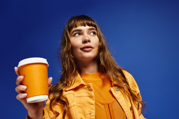 Stylish young woman enjoying a vibrant moment with a coffee cup against a bold backdrop