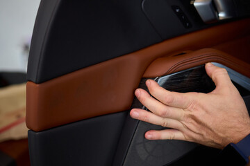 Skilled hands install a car door handle trim, highlighting craftsmanship and precision in design