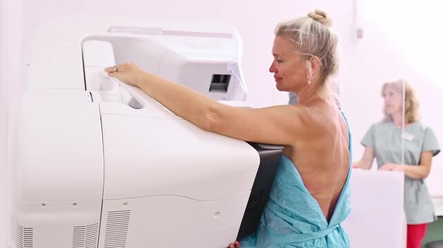 50-year-old woman undergoes mammography procedure on special medical equipment mammograph with the help of assistant in modern clinic. Regular medical examination, screening for breast cancer	
