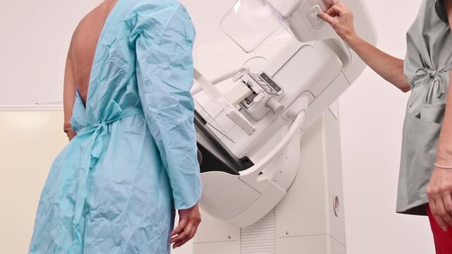 50-year-old woman undergoes mammography procedure on special medical equipment mammograph with the help of assistant in modern clinic. Regular medical examination, screening for breast cancer