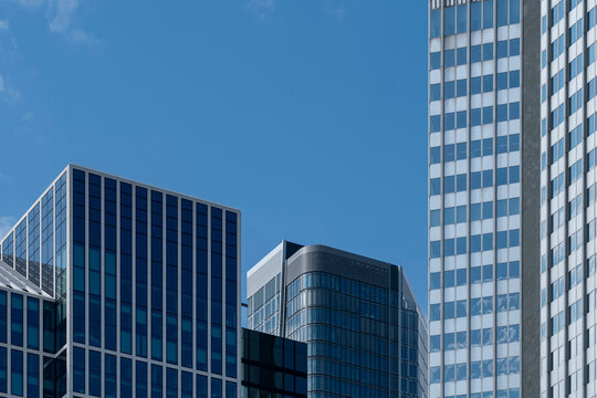 Modern towers in Frankfurt with glass facades under blue sky, corporate architecture and geometric rhythm representing European financial hub and innovative urban environment