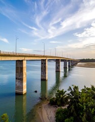 Obraz premium A long, modern concrete bridge stretches across a tranquil waterway, reflecting the serene sky and surrounding greenery.