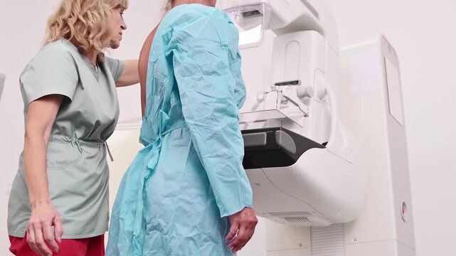 50-year-old woman undergoes mammography procedure on special medical equipment mammograph with the help of assistant in modern clinic. Regular medical examination, screening for breast cancer