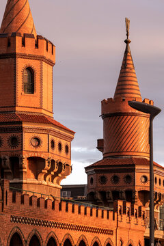 Red brick towers of Oberbaum Bridge in Berlin illuminated by sunset light, medieval revival architecture and urban heritage landmark along Spree River in German capital