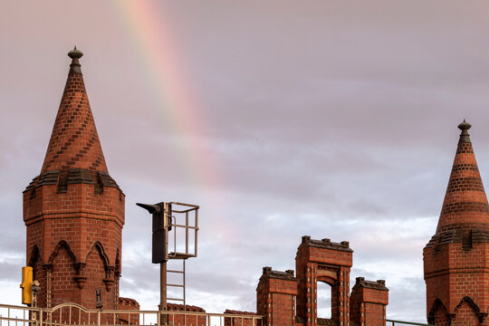 Twin towers of Oberbaum Bridge in Berlin with rainbow light behind, architectural heritage and urban icon representing city history and cultural identity at twilight