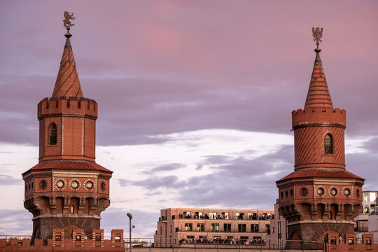 Fototapeta Wide view of Oberbaum Bridge twin towers in Berlin at dusk, historic red brick structure symbolizing connection, city identity and cultural landmark of German capital