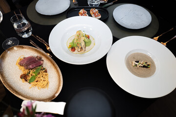Culinary Symphony on the Table: A captivating top-down composition of meticulously plated dishes on a sleek black surface, showcasing the art of fine dining and gastronomic excellence.