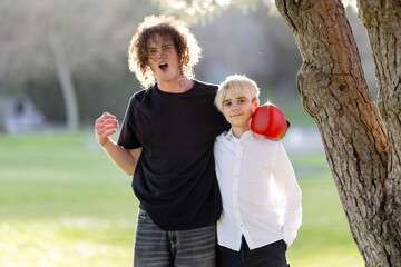 Older brother cheering up younger brother wearing boxing glove in park