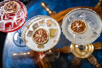Colorful cocktails served elegantly on a bar table. Three vibrant cocktails sit on a stylish bar...