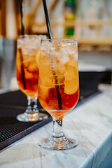 Chic bar serving refreshing cocktails. Two tall glasses of iced cocktails with lemon slices rest on a marble bar counter in a modern setting.