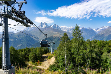 Cable car ascending over green forest and Georgia mountains in summer