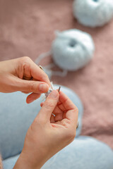 A woman sits on the floor and knits. Blue yarn and knitting needles. Women's hands